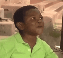 a young boy wearing a green shirt is looking up