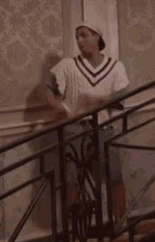 a man is standing on a set of stairs wearing a hat and a white sweater .