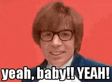 a man wearing glasses and a suit is smiling and saying `` yeah , baby ! yeah ! ''